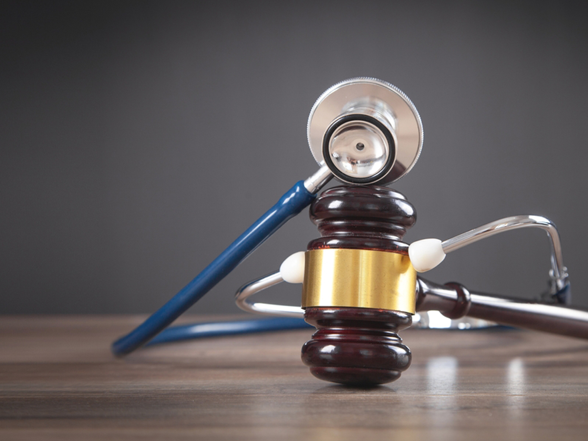 Judge gavel and stethoscope on the wooden table.