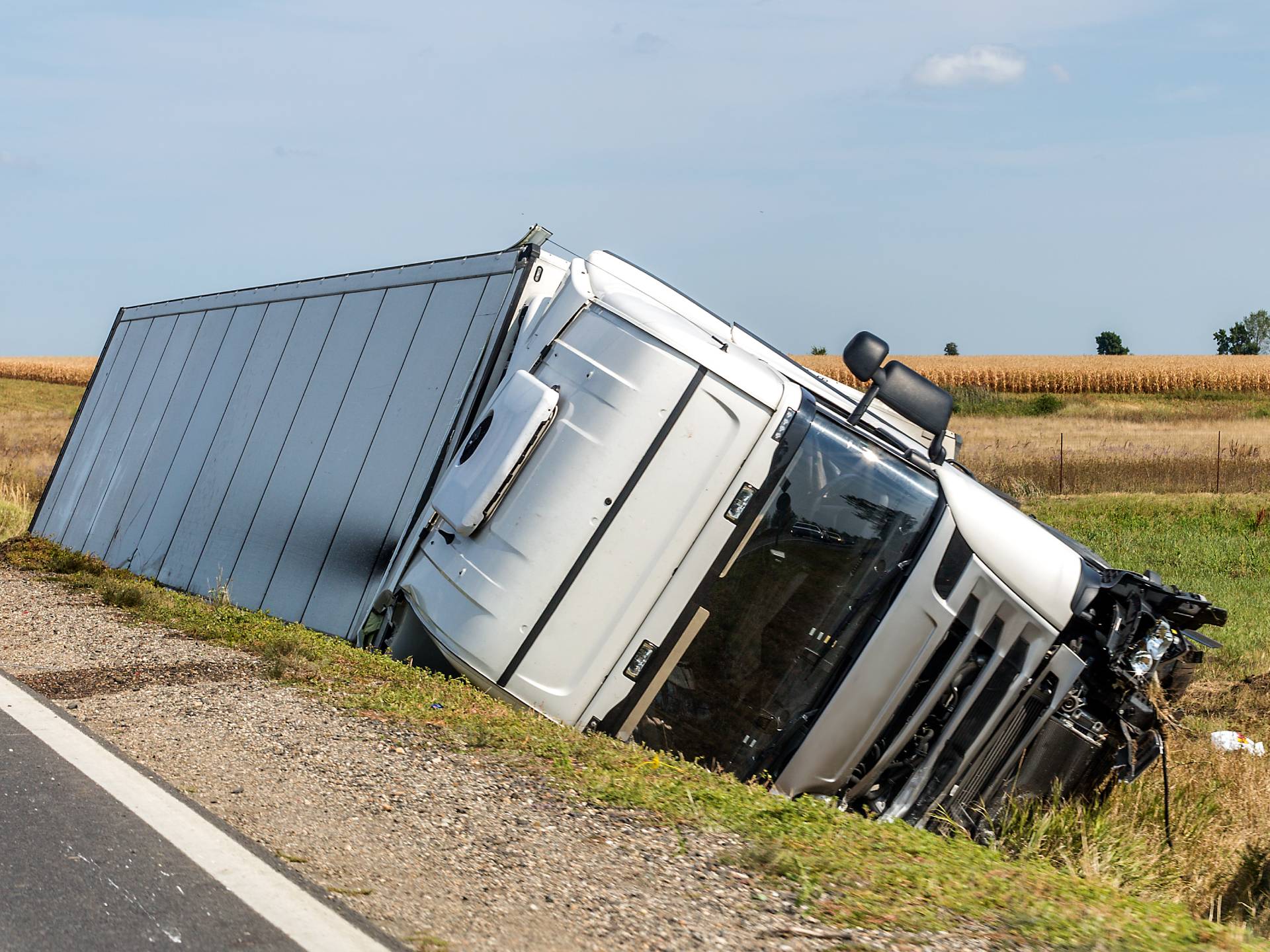 The large truck lies in a side ditch after the road accident.