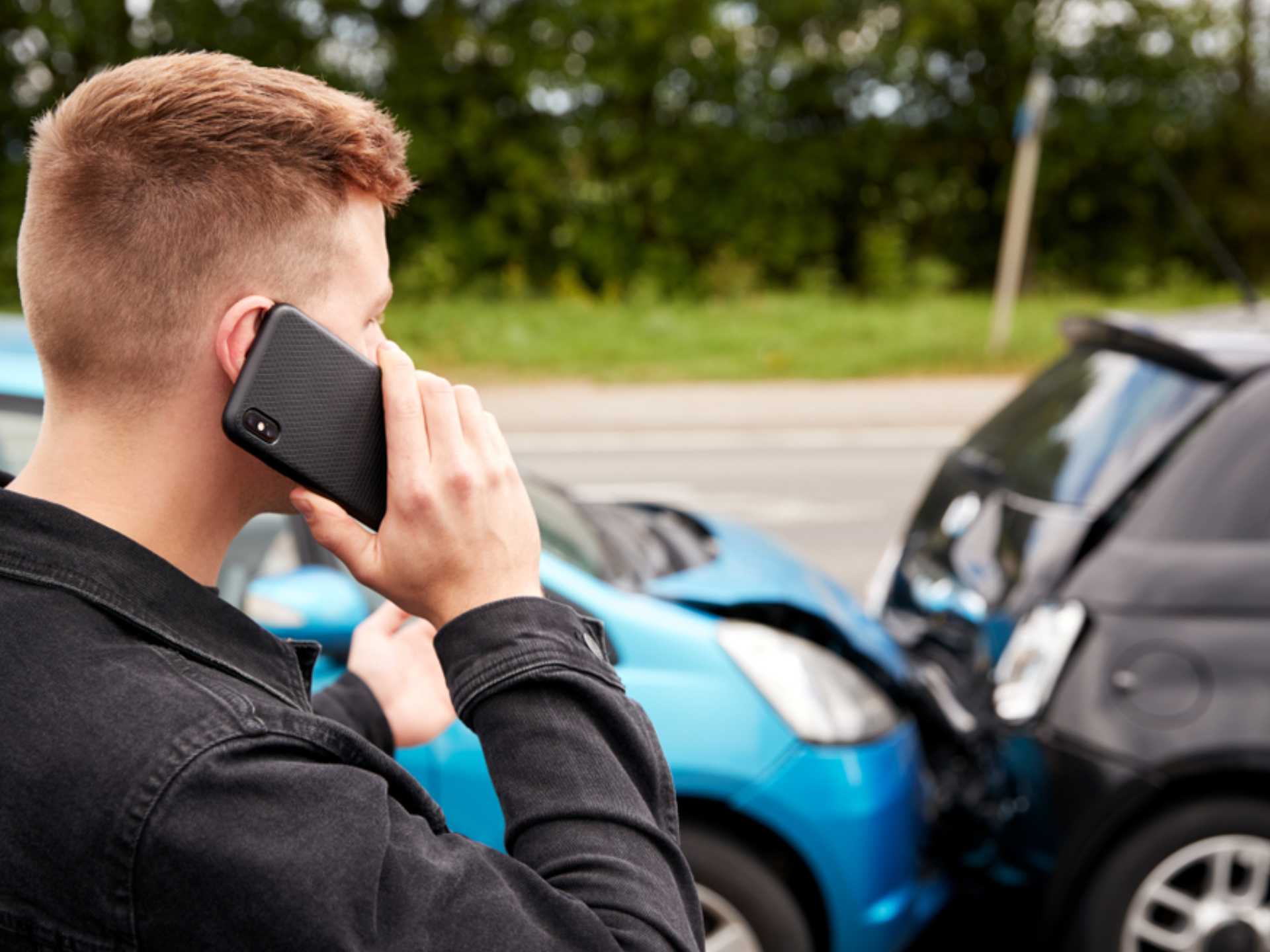 Young Male Motorist Involved In Car Accident Calling Insurance Company Or Recovery Service